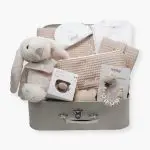 Canastilla bebé Dulces sueños compuesta por : Conejito de peluche BUNNY Peluche fabricado por Artesavi hecho a mano y confeccionado utilizando materiales de la más alta calidad, sus superficies son lavables. Este producto dispone de los ensayos de laboratorio y certificados según normativa Europea EN71-1 / EN71-2 / EN71-3 , estando exentos de tintes tóxicos y partes peligrosas garantizando así la total seguridad para los más pequeños. Medida : 32cm Personalizada la bandana con el nombre del bebé. Pelele manga larga aterciopelado, éste pijama además de estar diseñado especialmente para el descanso del bebé, mantiene la temperatura corporal del bebé al tiempo que se adapta perfectamente a su cuerpo lo que garantiza su comodidad durante el descanso. Composición : terciopelo 80% algodón y 20% polyester Gorrito bebé de algodón, personalizado mediante bordado. Cubo blandito de actividades de Little Dutch, este suave cubo de actividades contiene muchas actividades que estimulan los sentidos del bebé. Hay mucho por descubrir y jugar: varias etiquetas, diferentes texturas, un espejo y un sonajero que suena con cada movimiento. También hay una pequeña rana a la que le gusta jugar al escondite. Este juguete asegura momentos divertidos en el parque. Medidas : 15 x 15 x 15 cm Manta de piqué waffle algodón Manta ligera de piqué waffle y forro de coralina, ligera, calentita, fácil de plegar y limpiar. La coralina está fabricada con un innovador y renovado tejido polar, un moderno textil que le ofrece mejores propiedades térmicas. Se caracteriza por su tacto sedoso, textura muy suave, aspecto brillante, y mantener mejor el calor del bebé. Su tacto suave y agradable ofrece al bebé la opción de estar siempre junto a un peluche. Medidas aprox. : 70x100 cm Personalizable Precioso neceser bebé personalizable con la inicial o nombre del bebé donde podrás poner las cositas necesarias para su aseo, tanto si vas de paseo como de viaje. Neceser de piqué waffle