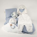 Canastilla bebé Dulces sueños compuesta por : Conejito de peluche BUNNY Peluche fabricado por Artesavi hecho a mano y confeccionado utilizando materiales de la más alta calidad, sus superficies son lavables. Este producto dispone de los ensayos de laboratorio y certificados según normativa Europea EN71-1 / EN71-2 / EN71-3 , estando exentos de tintes tóxicos y partes peligrosas garantizando así la total seguridad para los más pequeños. Medida : 32cm Personalizada la bandana con el nombre del bebé. Pelele manga larga aterciopelado, éste pijama además de estar diseñado especialmente para el descanso del bebé, mantiene la temperatura corporal del bebé al tiempo que se adapta perfectamente a su cuerpo lo que garantiza su comodidad durante el descanso. Composición : terciopelo 80% algodón y 20% polyester Gorrito bebé de algodón, personalizado mediante bordado. Pelota Montessori Sailors Bay Esta bola de agarre con su forma interesante es un gran desafío para su pequeño. Hay muchos lugares para agarrar y explorar con diferentes texturas y patrones. Es fácil de levantar para las manos pequeñas y cuando se mueve, el alegre sonido de la campana animará a su bebé. Su bonita decoración de veleros y faros, los nudos fáciles de agarrar y las diversas etiquetas estimularán los sentidos, desarrollarán el agarre y mantendrán a su bebé ocupado en el parque. Medidas 12 x 12 x 12cm Manta de piqué waffle algodón Manta ligera de piqué waffle y forro de coralina, ligera, calentita, fácil de plegar y limpiar. La coralina está fabricada con un innovador y renovado tejido polar, un moderno textil que le ofrece mejores propiedades térmicas. Se caracteriza por su tacto sedoso, textura muy suave, aspecto brillante, y mantener mejor el calor del bebé. Su tacto suave y agradable ofrece al bebé la opción de estar siempre junto a un peluche. Medidas aprox. : 70x100 cm Personalizable Precioso neceser bebé personalizable con la inicial o nombre del bebé donde