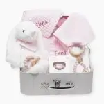 Canastilla bebé Bunny compuesta por peluche conejito con bandana personalizada con el nombre del bebé, chupetero de silicona modelo Momma personalizado, mordedor de silicona con figura de madera natural haya, chupete retro nordic personalizado, doudou muselina con aro de madera natural de haya personalizado, bandana de waffle algodón personalizado y neceser de waffle algodón personalizado. Todos los productos se presentan en una bonita y práctica maletita también personalizada con el nombre del bebé.