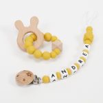 Conjunto chupetero personalizado y mordedor silicona MOMMA Mostaza. Sujetachupete silicona de grado alimentario libre de BPA, PVC, Ftalatos, cadmio y plomo. Pinza de madera y cordón de nylon de alta resistencia,bajo normativa europea EN12586:2007 (A1:2011) Mordedor de silicona de grado alimentario libre de BPA, PVC, Ftalatos, cadmio y plomo. Cordón de nylon de alta resistencia,bajo normativa europea EN12586:2007 (A1:2011) con figura de madera.
