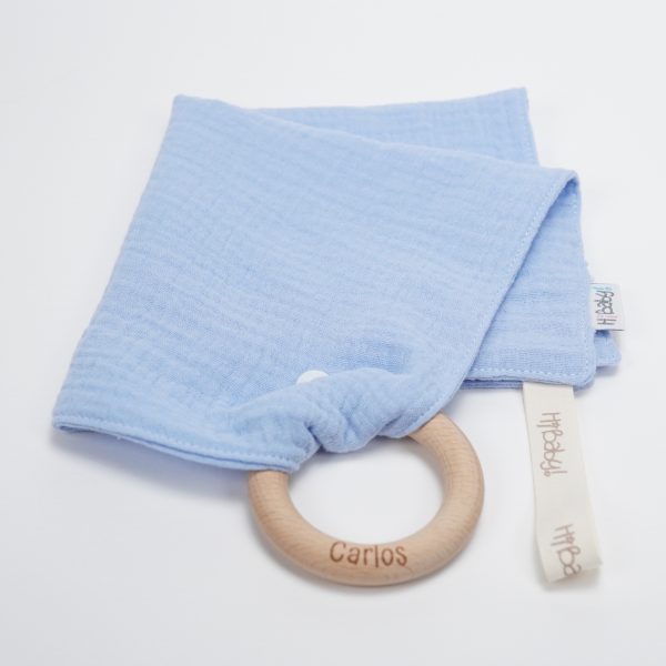 Doudou muselina con aro de madera natural de haya personalizado. La muselina es una tela de algodón orgánico muy suave,manejable, cómoda, esponjosa, ligera y agradable al tacto, tambien se denomina gasa de algodón. Todas las telas que utilizamos para el doudou muselina están certificadas con el sello STANDARD 100 by OEKO-TEX® que garantiza la ausencia de sustancias nocivas en el producto, esencial para el contacto directo con la piel para bebes y niñ@s de hasta tres años. Doudou muselina de doble capa, las medidas son 30cm x 30cm. Será uno de sus juguetes favoritos a modo de doudou. Para los más pequeños es muy fácil cogerlo, agarrarlo con fuerza y manejarlo. Calmará al bebé cuando empiece con la dentición. También puede utilizarse como chupetero. Confección artesanal elaborado por Hi Baby!