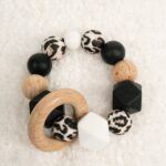 Mordedor de silicona de grado alimentario libre de BPA, PVC, Ftalatos, cadmio y plomo. Cordón de nylon de alta resistencia,bajo normativa europea EN12586:2007 (A1:2011) con aro en madera natural de haya. Color negro