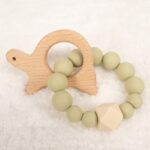 Mordedor de silicona con figura de tortuga en madera. Color verde matcha.