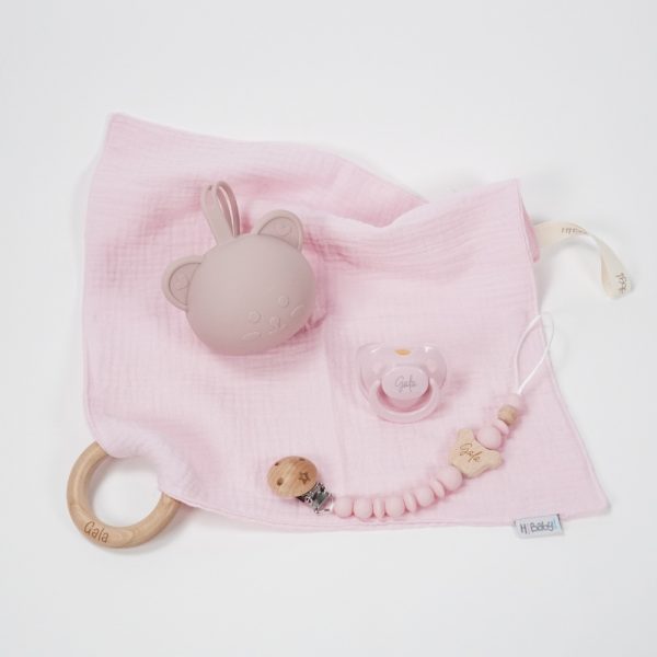Pack regalo Hi Baby compuesto por Doudou muselina con aro de madera natural de haya, personalizado con el nombre del bebé. La muselina es una tela de algodón orgánico muy suave,manejable, cómoda, esponjosa, ligera y agradable al tacto, tambien se denomina gasa de algodón. Todas las telas que utilizamos para el doudou muselina están certificadas con el sello STANDARD 100 by OEKO-TEX® que garantiza la ausencia de sustancias nocivas en el producto, esencial para el contacto directo con la piel para bebes y niñ@s de hasta tres años. Doudou muselina de doble capa, las medidas son 40cm x 40cm. Será uno de sus juguetes favoritos a modo de doudou. Para los más pequeños es muy fácil cogerlo, agarrarlo con fuerza y manejarlo. Calmará al bebé cuando empiece con la dentición. También se puede sustituir el aro por el chupete, actuando como chupetero. Personalizado el aro de madera con el nombre del bebé, confección artesanal elaborado por Hi Baby! Este guardachupetes bebé de silicona es perfecto para conservar los chupetes limpios hasta su uso, evitar que se pierdan y lo mejor, tenerlos siempre a mano cuando se necesita, con esta funda para chupetes colocada en las asas del cochecito se podrá recuperar rápidamente el chupete de bebé sin tener que buscar en su bolsa. El portachupetes es un accesorio clave y sobretodo muy práctico en cada salida, siendo el lugar ideal para guardar y mantenerlo siempre alejado de gérmenes y bacterias. El portachupetes para bebé es un accesorio esencial para muchos padres, ya que permite llevar y almacenar los chupetes del bebé de manera higiénica y organizada, puede guardar hasta 2 chupetes, y así disponer de un segundo chupete de repuesto, su tamaño compacto permite guardarla en cualquier bolsillo, pero si lo cuelgas del carro, lo agradecerás. Su correa de silicona facilita el transporte y evita que se pierda, puede ser útil para colgar el portachupetes del cochecito, de la bolsa del pañal o la muñeca del adulto