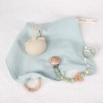 Pack regalo Hi Baby compuesto por Doudou muselina con aro de madera natural de haya, personalizado con el nombre del bebé. La muselina es una tela de algodón orgánico muy suave,manejable, cómoda, esponjosa, ligera y agradable al tacto, tambien se denomina gasa de algodón. Todas las telas que utilizamos para el doudou muselina están certificadas con el sello STANDARD 100 by OEKO-TEX® que garantiza la ausencia de sustancias nocivas en el producto, esencial para el contacto directo con la piel para bebes y niñ@s de hasta tres años. Doudou muselina de doble capa, las medidas son 30cm x 30cm. Será uno de sus juguetes favoritos a modo de doudou. Para los más pequeños es muy fácil cogerlo, agarrarlo con fuerza y manejarlo. Calmará al bebé cuando empiece con la dentición. También se puede sustituir el aro por el chupete, actuando como chupetero. Personalizado el aro de madera con el nombre del bebé, confección artesanal elaborado por Hi Baby! Este guardachupetes bebé de silicona es perfecto para conservar los chupetes limpios hasta su uso, evitar que se pierdan y lo mejor, tenerlos siempre a mano cuando se necesita, con esta funda para chupetes colocada en las asas del cochecito se podrá recuperar rápidamente el chupete de bebé sin tener que buscar en su bolsa. El portachupetes es un accesorio clave y sobretodo muy práctico en cada salida, siendo el lugar ideal para guardar y mantenerlo siempre alejado de gérmenes y bacterias. El portachupetes para bebé es un accesorio esencial para muchos padres, ya que permite llevar y almacenar los chupetes del bebé de manera higiénica y organizada, puede guardar hasta 2 chupetes, y así disponer de un segundo chupete de repuesto, su tamaño compacto permite guardarla en cualquier bolsillo, pero si lo cuelgas del carro, lo agradecerás. Su correa de silicona facilita el transporte y evita que se pierda, puede ser útil para colgar el portachupetes del cochecito, de la bolsa del pañal o la muñeca del adult