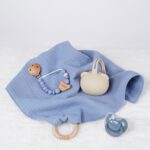 Pack regalo Hi Baby compuesto por Doudou muselina con aro de madera natural de haya, personalizado con el nombre del bebé. La muselina es una tela de algodón orgánico muy suave,manejable, cómoda, esponjosa, ligera y agradable al tacto, tambien se denomina gasa de algodón. Todas las telas que utilizamos para el doudou muselina están certificadas con el sello STANDARD 100 by OEKO-TEX® que garantiza la ausencia de sustancias nocivas en el producto, esencial para el contacto directo con la piel para bebes y niñ@s de hasta tres años. Doudou muselina de doble capa, las medidas son 40cm x 40cm. Será uno de sus juguetes favoritos a modo de doudou. Para los más pequeños es muy fácil cogerlo, agarrarlo con fuerza y manejarlo. Calmará al bebé cuando empiece con la dentición. También se puede sustituir el aro por el chupete, actuando como chupetero. Personalizado el aro de madera con el nombre del bebé, confección artesanal elaborado por Hi Baby! Este guardachupetes bebé de silicona es perfecto para conservar los chupetes limpios hasta su uso, evitar que se pierdan y lo mejor, tenerlos siempre a mano cuando se necesita, con esta funda para chupetes colocada en las asas del cochecito se podrá recuperar rápidamente el chupete de bebé sin tener que buscar en su bolsa. El portachupetes es un accesorio clave y sobretodo muy práctico en cada salida, siendo el lugar ideal para guardar y mantenerlo siempre alejado de gérmenes y bacterias. El portachupetes para bebé es un accesorio esencial para muchos padres, ya que permite llevar y almacenar los chupetes del bebé de manera higiénica y organizada, puede guardar hasta 2 chupetes, y así disponer de un segundo chupete de repuesto, su tamaño compacto permite guardarla en cualquier bolsillo, pero si lo cuelgas del carro, lo agradecerás. Su correa de silicona facilita el transporte y evita que se pierda, puede ser útil para colgar el portachupetes del cochecito, de la bolsa del pañal o la muñeca del adult