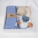 Pack regalo Hi Baby compuesto por Doudou muselina con aro de madera natural de haya, personalizado con el nombre del bebé. La muselina es una tela de algodón orgánico muy suave,manejable, cómoda, esponjosa, ligera y agradable al tacto, tambien se denomina gasa de algodón. Todas las telas que utilizamos para el doudou muselina están certificadas con el sello STANDARD 100 by OEKO-TEX® que garantiza la ausencia de sustancias nocivas en el producto, esencial para el contacto directo con la piel para bebes y niñ@s de hasta tres años. Doudou muselina de doble capa, las medidas son 40cm x 40cm. Será uno de sus juguetes favoritos a modo de doudou. Para los más pequeños es muy fácil cogerlo, agarrarlo con fuerza y manejarlo. Calmará al bebé cuando empiece con la dentición. También se puede sustituir el aro por el chupete, actuando como chupetero. Personalizado el aro de madera con el nombre del bebé, confección artesanal elaborado por Hi Baby! Este guardachupetes bebé de silicona es perfecto para conservar los chupetes limpios hasta su uso, evitar que se pierdan y lo mejor, tenerlos siempre a mano cuando se necesita, con esta funda para chupetes colocada en las asas del cochecito se podrá recuperar rápidamente el chupete de bebé sin tener que buscar en su bolsa. El portachupetes es un accesorio clave y sobretodo muy práctico en cada salida, siendo el lugar ideal para guardar y mantenerlo siempre alejado de gérmenes y bacterias. El portachupetes para bebé es un accesorio esencial para muchos padres, ya que permite llevar y almacenar los chupetes del bebé de manera higiénica y organizada, puede guardar hasta 2 chupetes, y así disponer de un segundo chupete de repuesto, su tamaño compacto permite guardarla en cualquier bolsillo, pero si lo cuelgas del carro, lo agradecerás. Su correa de silicona facilita el transporte y evita que se pierda, puede ser útil para colgar el portachupetes del cochecito, de la bolsa del pañal o la muñeca del adult