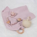 Pack regalo Hi Baby compuesto por Doudou muselina con aro de madera natural de haya, personalizado con el nombre del bebé. La muselina es una tela de algodón orgánico muy suave,manejable, cómoda, esponjosa, ligera y agradable al tacto, tambien se denomina gasa de algodón. Todas las telas que utilizamos para el doudou muselina están certificadas con el sello STANDARD 100 by OEKO-TEX® que garantiza la ausencia de sustancias nocivas en el producto, esencial para el contacto directo con la piel para bebes y niñ@s de hasta tres años. Doudou muselina de doble capa, las medidas son 40cm x 40cm. Será uno de sus juguetes favoritos a modo de doudou. Para los más pequeños es muy fácil cogerlo, agarrarlo con fuerza y manejarlo. Calmará al bebé cuando empiece con la dentición. También se puede sustituir el aro por el chupete, actuando como chupetero. Personalizado el aro de madera con el nombre del bebé, confección artesanal elaborado por Hi Baby! Este guardachupetes bebé de silicona es perfecto para conservar los chupetes limpios hasta su uso, evitar que se pierdan y lo mejor, tenerlos siempre a mano cuando se necesita, con esta funda para chupetes colocada en las asas del cochecito se podrá recuperar rápidamente el chupete de bebé sin tener que buscar en su bolsa. El portachupetes es un accesorio clave y sobretodo muy práctico en cada salida, siendo el lugar ideal para guardar y mantenerlo siempre alejado de gérmenes y bacterias. El portachupetes para bebé es un accesorio esencial para muchos padres, ya que permite llevar y almacenar los chupetes del bebé de manera higiénica y organizada, puede guardar hasta 2 chupetes, y así disponer de un segundo chupete de repuesto, su tamaño compacto permite guardarla en cualquier bolsillo, pero si lo cuelgas del carro, lo agradecerás. Su correa de silicona facilita el transporte y evita que se pierda, puede ser útil para colgar el portachupetes del cochecito, de la bolsa del pañal o la muñeca del adult