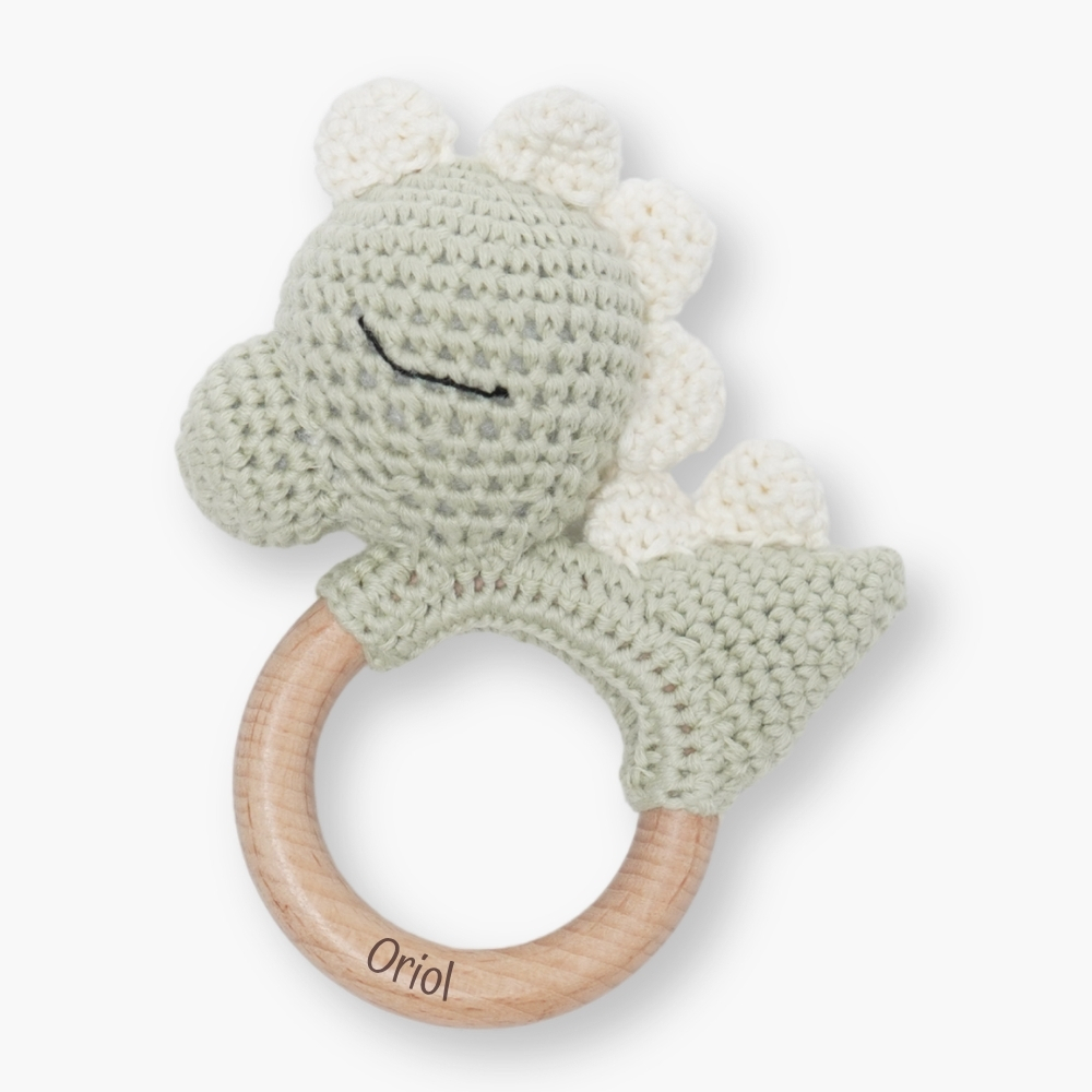 Sonajero crochet dino personalizado con diseño de dinosaurio, ideal para acompañar los primeros descubrimientos del bebé. Gracias a su diseño minimalista y personalizado, se convierte en un recuerdo único y especial que las familias conservarán con cariño. El aro de madera natural incluye el nombre del bebé grabado con láser, aportando a este sonajero crochet para bebé un acabado elegante, fino y duradero. Esta personalización convierte cada pieza en un detalle exclusivo y muy especial para regalar. Cada sonajero crochet personalizado con nombre está pensado para crear un recuerdo bonito desde los primeros meses del bebé. El tamaño del anillo es ideal para la mano del bebé y su textura suave y delicada es perfecta para la estimulación táctil ayudando a desarrollar la motricidad fina del bebé.