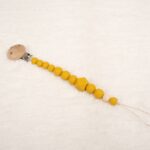 Sujetachupete silicona de grado alimentario libre de BPA, PVC, Ftalatos, cadmio y plomo. Pinza de madera y cordón de nylon de alta resistencia,bajo normativa europea EN12586:2007 (A1:2011) Color mostaza