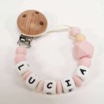 Sujetachupete de silicona personalizado con pinza de madera color rosa.