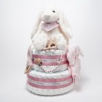 Tarta de pañales de dos pisos compuesta por 44 unidades marca Dodot sensitive, peluche principal conejito con bandana personalizada , mordedor orejitas de piqué waffle, algodón y madera personalizado, sujeta chupetes de silicona personalizado, cepillo y peine para bebé de madera 100% natural personalizados, bandana de piqué waffle y algodón, mordedor de silicona y madera, dou dou animalito. Dimensiones altura 45cm x 26cm ancho.