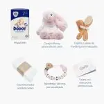 Tarta de pañales de dos pisos compuesta por 44 unidades marca Dodot Sensitive T2, peluche principal conejito personalizado, conjunto cepillo y peine bebé de madera personalizado con el nombre del bebé, sujeta chupetes de silicona personalizado con el nombre del bebé y juego calcetines bebé. Dimensiones altura 45cm x 26cm ancho. Color Rosa bebé