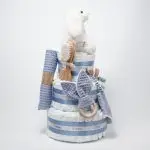 Tarta de pañales 3 pisos SPECIAL CAKE compuesto por 52 unidades marca Dodot sensitive, peluche principal conejito personalizado, sujeta chupetes de silicona Momma, mordedor orejitas piqué waffle algodón con aro de madera personalizado con el nombre del bebé, cepillo y peine para bebé de madera 100% natural personalizado con el nombre del bebé, mordedor de silicona Momma, bandana de piqué waffle y Doudou animalito personalizado con el nombre del bebé. Dimensiones altura 55cm x 26cm ancho. Color Azul Jean.