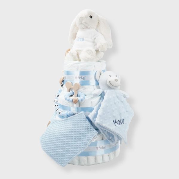 Tarta de pañales 3 pisos SPECIAL CAKE compuesto por 52 unidades marca Dodot sensitive, peluche principal conejito personalizado, sujeta chupetes de silicona Momma, mordedor orejitas piqué waffle algodón con aro de madera personalizado con el nombre del bebé, cepillo y peine para bebé de madera 100% natural personalizado con el nombre del bebé, mordedor de silicona Momma, bandana de piqué waffle y Doudou animalito personalizado con el nombre del bebé. Dimensiones altura 55cm x 26cm ancho. Color azul bebé