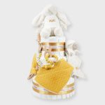Tarta de pañales 3 pisos SPECIAL CAKE compuesto por 52 unidades marca Dodot sensitive, peluche principal conejito personalizado, sujeta chupetes de silicona Momma, mordedor orejitas piqué waffle algodón con aro de madera personalizado con el nombre del bebé, cepillo y peine para bebé de madera 100% natural personalizado con el nombre del bebé, mordedor de silicona Momma, bandana de piqué waffle y Doudou animalito personalizado con el nombre del bebé. Dimensiones altura 55cm x 26cm ancho. Color Mostaza.