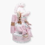 Tarta de pañales 3 pisos SPECIAL CAKE compuesto por 52 unidades marca Dodot sensitive, peluche principal conejito personalizado, sujeta chupetes de silicona Momma, mordedor orejitas piqué waffle algodón con aro de madera personalizado con el nombre del bebé, cepillo y peine para bebé de madera 100% natural personalizado con el nombre del bebé, mordedor de silicona Momma, bandana de piqué waffle y Doudou animalito personalizado con el nombre del bebé. Dimensiones altura 55cm x 26cm ancho. Color Rosa bebé.