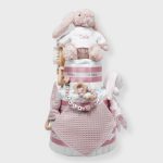 Tarta de pañales 3 pisos SPECIAL CAKE compuesto por 52 unidades marca Dodot sensitive, peluche principal conejito personalizado, sujeta chupetes de silicona Momma, mordedor orejitas piqué waffle algodón con aro de madera personalizado con el nombre del bebé, cepillo y peine para bebé de madera 100% natural personalizado con el nombre del bebé, mordedor de silicona Momma, bandana de piqué waffle y Doudou animalito personalizado con el nombre del bebé. Dimensiones altura 55cm x 26cm ancho. Color Rosa palo.