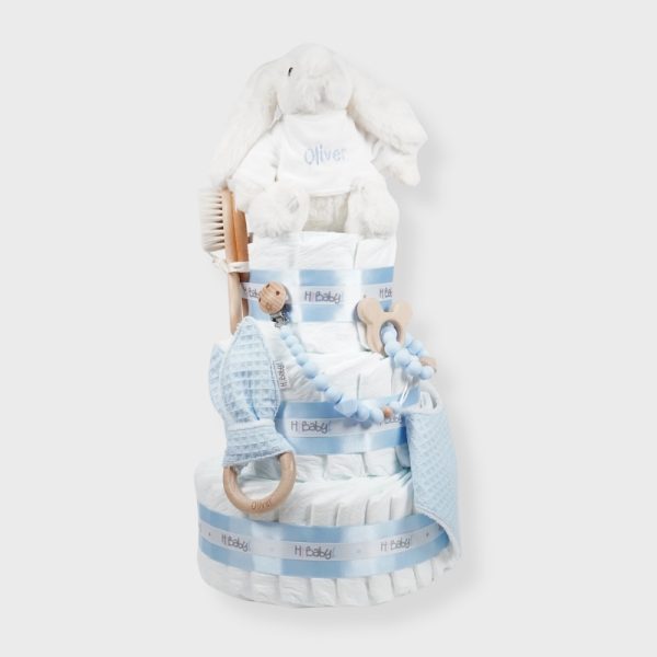 Tarta de pañales Sweet Cake de tres pisos compuesto por 52 unidades marca Dodot sensitive T2, peluche principal conejito personalizado, sujeta chupetes de silicona personalizable, mordedor orejitas piqué waffle algodón y madera personalizado, cepillo para bebé de madera 100% natural personalizado, mordedor de silicona y bandana de piqué waffle personalizable. Dimensiones altura 55cm x 26cm ancho. Color Azul