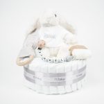 Tarta de pañales 1 piso LITTLE BUNNY compuesto por 28 unidades marca Dodot Sensitive T2, peluche principal conejito personalizado, mordedor de piqué waffle de algodón y aro de madera personalizado, sujeta chupetes de silicona modelo Momma personalizado y juego calcetines bebé de algodón. Dimensiones altura 35cm x 22cm ancho. Color Gris