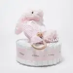 Tarta de pañales 1 piso LITTLE BUNNY compuesto por 28 unidades marca Dodot Sensitive T2, peluche principal conejito personalizado, mordedor de piqué waffle de algodón y aro de madera personalizado, sujeta chupetes de silicona modelo Momma personalizado y juego calcetines bebé de algodón. Dimensiones altura 35cm x 22cm ancho.