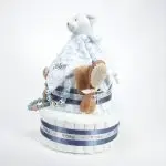 Tarta de pañales 2 pisos BABY DOUDOU compuesta por 44 unidades marca Dodot Sensitive T2, peluche principal Dou Dou personalizado, mordedor orejitas de piqué waffle algodón y madera personalizado, sujeta chupetes de silicona personalizado, cepillo y peine para bebé de madera 100% natural personalizados, mordedor de silicona y madera. Dimensiones altura 40cm x 26cm ancho.