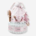 Tarta de pañales 2 pisos BABY RATTLE compuesta por 44 unidades marca Dodot Sensitive T2, peluche principal Dou Dou personalizable, mordedor orejitas de crochet y madera de haya personalizado, sujeta chupetes de silicona personalizado, conjunto de cepillo y peine bebé de madera personalizados. Dimensiones altura 40cm x 26cm ancho. Color Rosa bebé