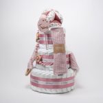 Tarta de pañales de 3 pisos compuesto por 52 unidades marca Dodot sensitive, pelota sensorial Montessori de Little Dutch, mordedor orejitas de tela piqué waffle algodón y aro de madera natural personalizado con el nombre del bebé, bandana de tela piqué waffle algodón personalizable, chupetero de silicona y crochet con pinza de madera natural de haya, paño de lactancia de piqué waffle algodón, muñeca ANNA de Little Dutch 35cm. Stick de madera personalizado con el nombre del bebé. Dimensiones altura 42cm x 27cm ancho. Color Rosa palo