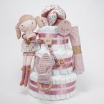Tarta de pañales de 3 pisos compuesto por 52 unidades marca Dodot sensitive, pelota sensorial Montessori de Little Dutch, mordedor orejitas de tela piqué waffle algodón y aro de madera natural personalizado con el nombre del bebé, bandana de tela piqué waffle algodón personalizable, chupetero de silicona y crochet con pinza de madera natural de haya, paño de lactancia de piqué waffle algodón, muñeca ANNA de Little Dutch 35cm. Stick de madera personalizado con el nombre del bebé. Dimensiones altura 42cm x 27cm ancho. Color Rosa palo