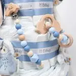 Tarta de pañales de 3 pisos JIMMY compuesto por 52 unidades marca Dodot sensitive, pelota sensorial Montessori de Little Dutch, chupetero de silicona, mordedor de silicona con figura de madera natural de haya, muñeco JIMMY de Little Dutch 35cm., Chupetero muselina buho de Little Dutch, Doudou Sailors bay de Little Dutch, stick de madera personalizado con el nombre del bebé. Dimensiones altura 42cm x 27cm ancho. Color Azul jean
