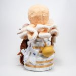 Tarta de pañales de tres pisos compuesto por 52 unidades marca Dodot sensitive, peluche principal Pulpo dorado 40cm, increiblemente suave y decorativo, chupetero de silicona con pinza de silicona de grado alimentario libre de BPA, PVC, Ftalatos, cadmio y plomo, mordedor de silicona con figura de madera natural haya, bandana secababitas de piqué waffle, chupetero de tela estrella de Little Dutch 15cm x 15cm, cepillo y peine personalizados con el nombre del bebé de madera natural, sonajero conejo orejitas de Artesavi 35cm, stick de madera personalizado con el nombre del bebé. Dimensiones altura 45cm x 26cm ancho. Color Melocotón
