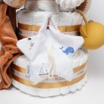 Tarta de pañales de tres pisos compuesto por 52 unidades marca Dodot sensitive, peluche principal Pulpo dorado 40cm, increiblemente suave y decorativo, chupetero de silicona con pinza de silicona de grado alimentario libre de BPA, PVC, Ftalatos, cadmio y plomo, mordedor de silicona con figura de madera natural haya, bandana secababitas de piqué waffle, chupetero de tela estrella de Little Dutch 15cm x 15cm, cepillo y peine personalizados con el nombre del bebé de madera natural, sonajero conejo orejitas de Artesavi 35cm, stick de madera personalizado con el nombre del bebé. Dimensiones altura 45cm x 26cm ancho. Color Melocotón