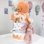 Tarta de pañales de tres pisos compuesto por 52 unidades marca Dodot sensitive, peluche principal Pulpo dorado 40cm, increiblemente suave y decorativo, chupetero de silicona con pinza de silicona de grado alimentario libre de BPA, PVC, Ftalatos, cadmio y plomo, mordedor de silicona con figura de madera natural haya, bandana secababitas de piqué waffle, chupetero de tela estrella de Little Dutch 15cm x 15cm, cepillo y peine personalizados con el nombre del bebé de madera natural, sonajero conejo orejitas de Artesavi 35cm, stick de madera personalizado con el nombre del bebé. Dimensiones altura 45cm x 26cm ancho. Color Melocotón