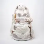 Tarta pañales V. Sunny Champagne compuesto por 84 unidades marca Dodot, peluche principal Mocca de Teddykompaniet 25 cm, chupetero de silicona de grado alimentario libre de BPA, PVC, Ftalatos, cadmio y plomo, bandana secababitas, chupete personalizado, mordedor orejitas y capa de baño de piqué waffle personalizada de Hi Baby, Doudou baby bunny personalizado, conjunto de cepillo y peine de madera personalizado hecho con materiales 100% naturales de lana de cabra y madera de haya, ofreciendo una experiencia cómoda y suave para tu bebé. Ideal para el cuero cabelludo sensible de los más pequeños, guardachupetes de silicona perfecto para guardar el chupete cuando no se está usando, body de babidu personalizado con el dibujo de un conejito y el nombre del bebé. Dimensiones altura 56cm x 30cm ancho. Color Champagne