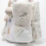 Tarta pañales V. Sunny Champagne compuesto por 84 unidades marca Dodot, peluche principal Mocca de Teddykompaniet 25 cm, chupetero de silicona de grado alimentario libre de BPA, PVC, Ftalatos, cadmio y plomo, bandana secababitas, chupete personalizado, mordedor orejitas y capa de baño de piqué waffle personalizada de Hi Baby, Doudou baby bunny personalizado, conjunto de cepillo y peine de madera personalizado hecho con materiales 100% naturales de lana de cabra y madera de haya, ofreciendo una experiencia cómoda y suave para tu bebé. Ideal para el cuero cabelludo sensible de los más pequeños, guardachupetes de silicona perfecto para guardar el chupete cuando no se está usando, body de babidu personalizado con el dibujo de un conejito y el nombre del bebé. Dimensiones altura 56cm x 30cm ancho. Color Champagne