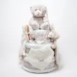 Tarta pañales V. Sunny Champagne compuesto por 84 unidades marca Dodot, peluche principal Mocca de Teddykompaniet 25 cm, chupetero de silicona de grado alimentario libre de BPA, PVC, Ftalatos, cadmio y plomo, bandana secababitas, chupete personalizado, mordedor orejitas y capa de baño de piqué waffle personalizada de Hi Baby, Doudou baby bunny personalizado, conjunto de cepillo y peine de madera personalizado hecho con materiales 100% naturales de lana de cabra y madera de haya, ofreciendo una experiencia cómoda y suave para tu bebé. Ideal para el cuero cabelludo sensible de los más pequeños, guardachupetes de silicona perfecto para guardar el chupete cuando no se está usando, body de babidu personalizado con el dibujo de un conejito y el nombre del bebé. Dimensiones altura 56cm x 30cm ancho. Color Champagne