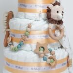 Tarta de pañales Baby Lion 3Pisos regalo bebé recién nacido compuesta por.- 52 unidades marca Dodot sensitive T2, peluche principal bebé león, mordedor de silicona con figuras de madera de haya, chupetero de silicona y madera con figurita personalizada, conjunto de cepillo y peine de madera personalizados, chupetero de tela algodón y coralina extrasuave 20cm x 20cm, estampado original Selva. Sonajero crochet figurita león con aro de madera personalizado con el nombre del bebé, toalla capa de baño Selva de Hi Baby! 100% algodón.medidas 80cm x 80 cm Dimensiones tarta, altura 42cm x 26cm ancho. Peluche León apto para +0 meses, producido con tejidos muy suaves y detalles bordados, ojos y nariz, divertido peluche fácil de coger para las manos más pequeñas con certificados adicionales a los obligatorios como los de saliva y exclusión de tintes tóxicos en los tejidos, con la máxima garantía para los mas pequeños. Está fabricado en material de alta calidad muy suave y apto para el bebé. Superficie lavable. Homologación europea EN71-1- Lavado: a mano o máquina a 30° C, Se recomienda utilizar un programa y detergente suave. No utilizar secadora. Medida 32cm. Peso del producto 200 g.