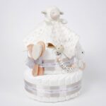 Tarta de pañales de dos pisos compuesta por 44 unidades marca Dodot, peluche principal Doudou personalizable, mordedor orejitas de crochet y madera, sujeta chupetes de silicona personalizado, conjunto de cepillo y peine bebé de madera personalizados. Dimensiones altura 40cm x 26cm ancho. Color Beige