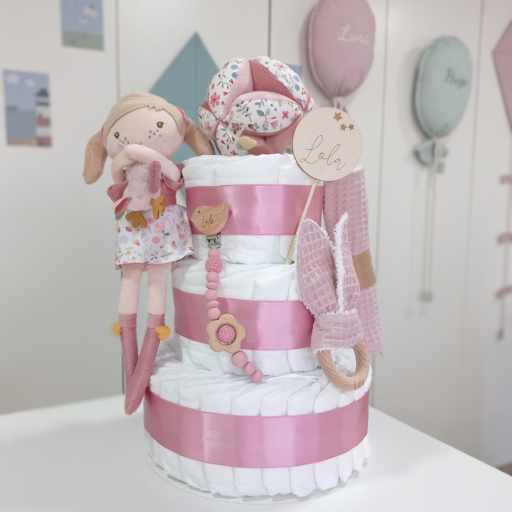 Tarta de pañales de 3 pisos ANNA compuesto por 52 unidades marca Dodot sensitive, pelota sensorial Montessori de Little Dutch, mordedor orejitas de tela piqué waffle algodón y aro de madera natural personalizado con el nombre del bebé, bandana de tela piqué waffle algodón personalizable, chupetero de silicona y crochet con pinza de madera natural de haya, paño de lactancia de piqué waffle algodón, muñeca ANNA de Little Dutch 35cm. Stick de madera personalizado con el nombre del bebé. Dimensiones altura 42cm x 27cm ancho. Color Rosa oscuro