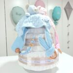 Tarta de pañales para gemelos o mellizos de 3 pisos, es el regalo perfecto para dar la bienvenida a los bebés recién nacidos. Contenido de la tarta de pañales para gemelos 3 pisos : 72 unidades pañales Dodot sensitive T2 alta absorción. Dos Dou Dou a conjunto con el color elegido, personalizados. Dos Sujetachupetes de silicona personalizados. Dos Mordedores orejitas de waffle, Dos bandanas secababitas de algodón waffle. Tarjeta de felicitación personalizada con el nombre de los bebés, dónde podrás expresar tú mensaje de bienvenida. Envuelto en papel de celofán transparente con lazo realizado en cinta especial Hi Baby. Caja de cartón con protección para el transporte. Dimensiones y color de la tarta de pañales para gemelos de 3 pisos: Altura 38cm. Ancho:26cm. Color: rosa, azul, gris, beige o toffee. Especificaciones de los productos que se incluyen en esta tarta de pañales para gemelos recién nacido: 3 pisos compuesto por 72 pañales Dodot® Sensitive T2 de alta absorción y protección con capa dermo confort, por lo que no irritan la piel delicada del bebé.Dos Dou Dou 28cm x 28cm confeccionado utilizando únicamente materiales de máxima calidad certificado según normativa Europea garantizando la total seguridad para los pequeños. Dos Mordedores orejitas de waffle y madera. Dos Sujetachupetes de silicona personalizados, Dos bandanas secababitas de algodón waffle, Todas nuestras telas están certificadas con el sello  STANDARD 100 by OEKO-TEX® que garantiza la ausencia de sustancias nocivas en el producto, apto para articulos que puedan estar en contacto directo con la piel para bebes y niñ@s de hasta tres años. El algodón waffle es una tela muy suave,manejable y cómoda, tremendamente esponjosa adquiere su nombre por los cuadraditos en relieve, que hacen la forma de un gofre o bien de un nido de abeja. Medidas.- 29cm x 15cm Realizado a mano con cierre de velcro muy cómodo para su ajuste. Personalizable con el nombre de los bebés.