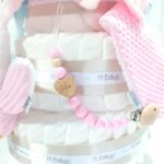 Tarta de pañales para gemelos o mellizos de 3 pisos, es el regalo perfecto para dar la bienvenida a los bebés recién nacidos. Contenido de la tarta de pañales para gemelos 3 pisos : 72 unidades pañales Dodot sensitive T2 alta absorción. Dos Dou Dou a conjunto con el color elegido, personalizados. Dos Sujetachupetes de silicona personalizados. Dos Mordedores orejitas de waffle, Dos bandanas secababitas de algodón waffle. Tarjeta de felicitación personalizada con el nombre de los bebés, dónde podrás expresar tú mensaje de bienvenida. Envuelto en papel de celofán transparente con lazo realizado en cinta especial Hi Baby. Caja de cartón con protección para el transporte. Dimensiones y color de la tarta de pañales para gemelos de 3 pisos: Altura 38cm. Ancho:26cm. Color: rosa, azul, gris, beige o toffee. Especificaciones de los productos que se incluyen en esta tarta de pañales para gemelos recién nacido: 3 pisos compuesto por 72 pañales Dodot® Sensitive T2 de alta absorción y protección con capa dermo confort, por lo que no irritan la piel delicada del bebé.Dos Dou Dou 28cm x 28cm confeccionado utilizando únicamente materiales de máxima calidad certificado según normativa Europea garantizando la total seguridad para los pequeños. Dos Mordedores orejitas de waffle y madera. Dos Sujetachupetes de silicona personalizados, Dos bandanas secababitas de algodón waffle, Todas nuestras telas están certificadas con el sello  STANDARD 100 by OEKO-TEX® que garantiza la ausencia de sustancias nocivas en el producto, apto para articulos que puedan estar en contacto directo con la piel para bebes y niñ@s de hasta tres años. El algodón waffle es una tela muy suave,manejable y cómoda, tremendamente esponjosa adquiere su nombre por los cuadraditos en relieve, que hacen la forma de un gofre o bien de un nido de abeja. Medidas.- 29cm x 15cm Realizado a mano con cierre de velcro muy cómodo para su ajuste. Personalizable con el nombre de los bebés.