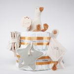 Tarta de pañales de 2 pisos compuesto por 44 unidades marca Dodot sensitive, peluche principal pequeña oca de Li ttle Dutch 18cm de altura está hecha con una felpa increiblemente suave ideal para el bebé, Doudou oca personalizado de Little Dutch hecho con felpa muy suave aportando comodidad al bebé, cuando duerme dispone de varias etiquetas para tocar y sentir estimulando los sentidos del bebé los nudos y patas son perfectos para acurrucarse o masticar cuando empiezan a salir los dientes puede actuar como chupetero tiene enganche para chupete medidas 24cm x 24cm, chupetero de tela estrella de Little Dutch 15cm x 15cm. Librito blando actividades Little Dutch, Chupetero de tela algodón pequeños gansos de Hi Baby! Stick de madera personalizado con el nombre del bebé. Dimensiones altura 38cm x 26cm ancho. Color Mostaza